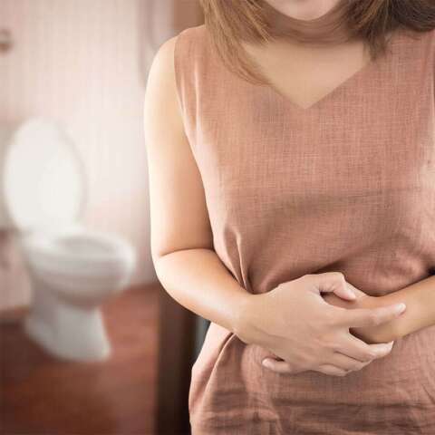 Frau hält sich verkrampft ihren Bauch.